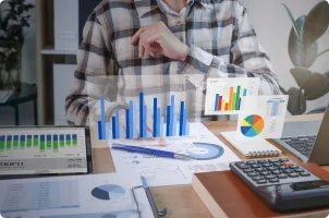 A person works at a desk with charts and a calculator.